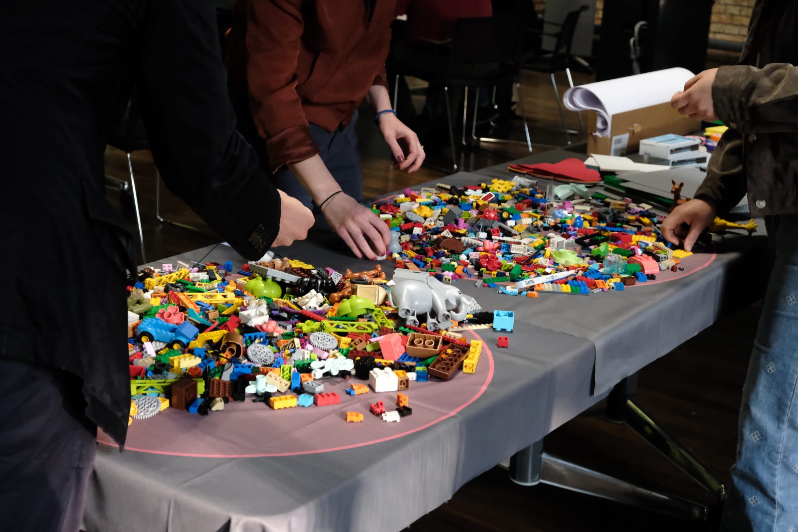 Hände suchen Steine aus einem bunten LEGO®-Haufen während eines Workshops