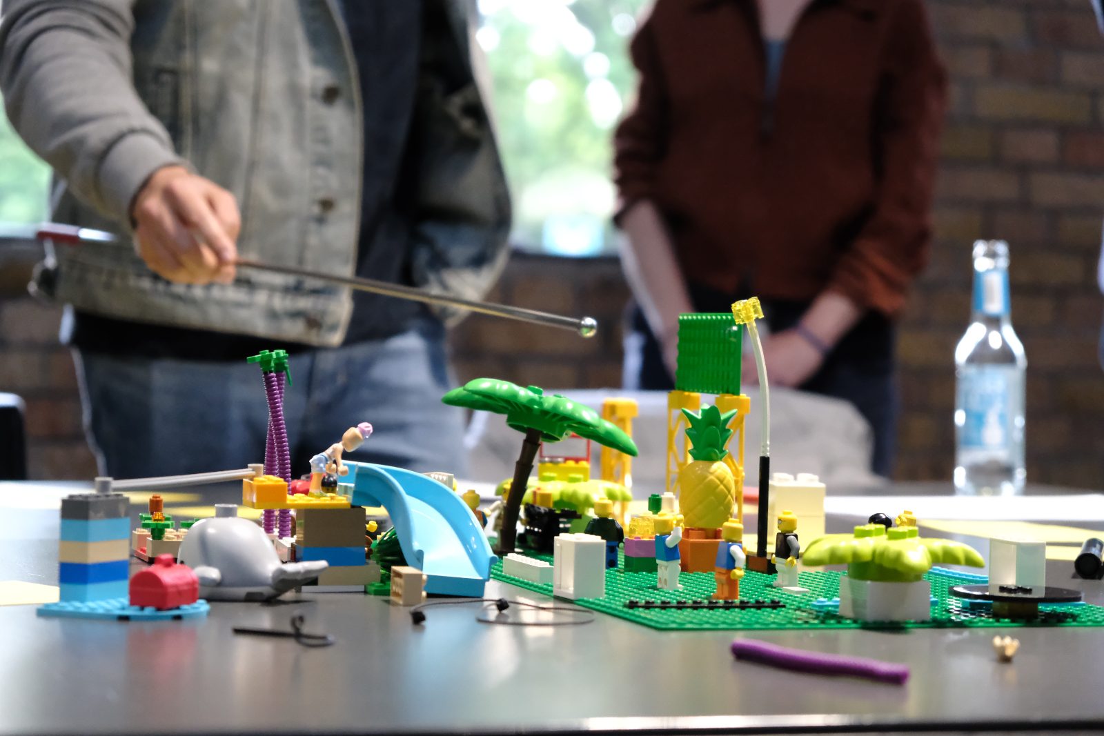 Ein gebautes LEGO® SERIOUS PLAY® Modell auf dem Tisch, im Hintergrund Teilnehmende